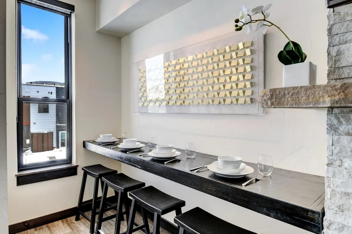 A contemporary dining area centered around a long wooden table, accented by decorative wall art and a large window. The space is relaxed yet refined, ideal for lingering breakfasts, convivial gatherings, or sharing stories after a day’s adventure.