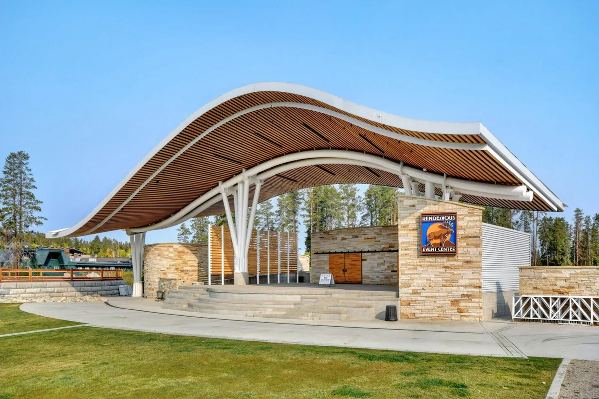 This image features the iconic curved roof and stone facade of the Hideaway Park amphitheater, surrounded by open space and wooden accents. The amphitheater is ready for outdoor concerts, events, and community gatherings.